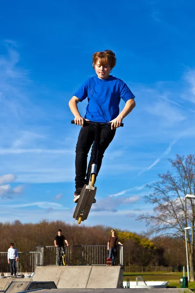 Ребенок летит по воздуху со своим скутером — стоковое фото