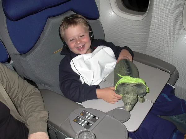 Menino está voando classe executiva na aeronave com seu brinquedo confortável — Fotografia de Stock