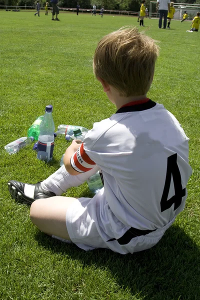 Erschöpfter Junge macht Pause in der Halbzeit eines Fußballspiels — Stockfoto