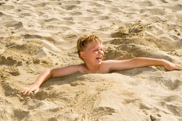 少年は砂浜のビーチに身を掘ってと楽しいのたくさん持っています。 — ストック写真