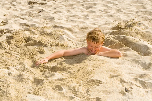 Fiú magát belesüllyed a homokos strandtól, és van egy csomó móka — Stock Fotó