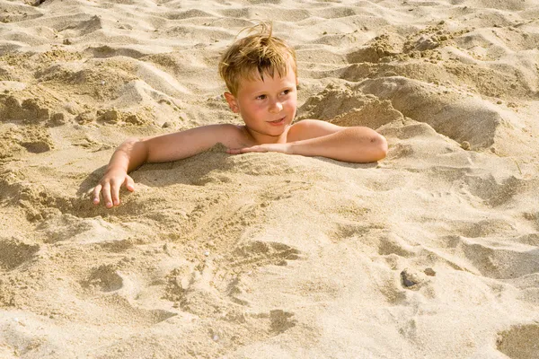 少年は砂浜のビーチに身を掘ってと楽しいのたくさん持っています。 — ストック写真
