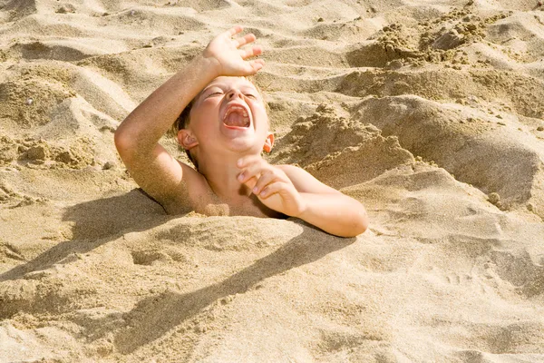 Fiú magát belesüllyed a homokos strandtól, és van egy csomó móka — Stock Fotó