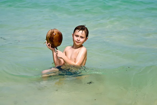 男孩在美丽的海滩上与椰子玩耍 — 图库照片