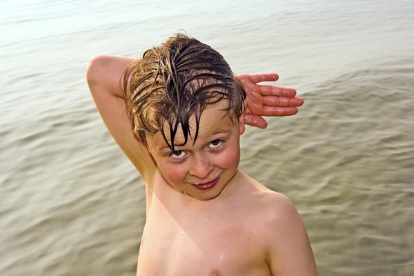 Junge posiert mit Handzeichen im Meer Stockbild