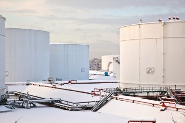 White tanks in tank farm with snow in winter clipart