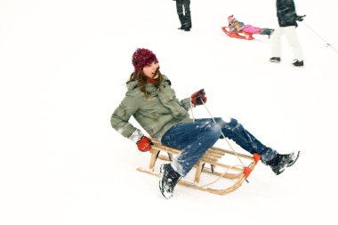 Girl enjoys sledging in winter on beautiful white snow clipart