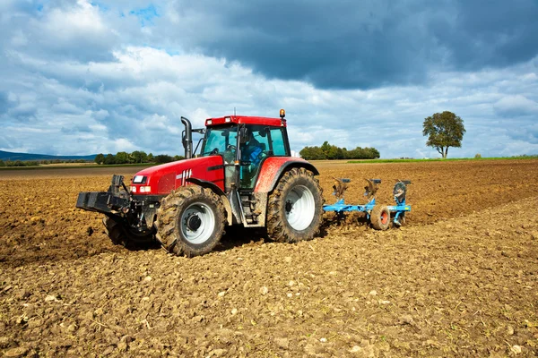 Traktor mit Pflug auf Feld — Stockfoto