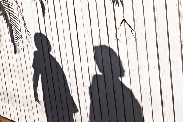 Sombra de un niño con madre en una valla de madera — Foto de Stock