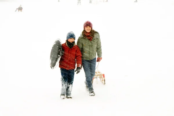 Ragazza e ragazzo a piedi sulla collina nella neve pesante — Foto Stock