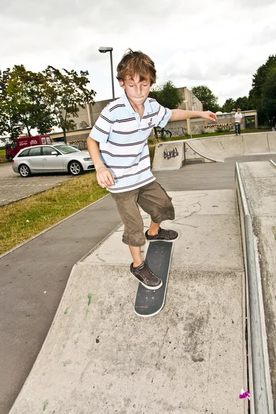 Niño patinaje en el parque de skate y se divierte —  Fotos de Stock