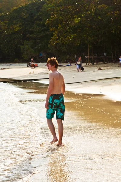 Niño está caminando a lo largo de la hermosa playa en la luz de fondo — Foto de Stock
