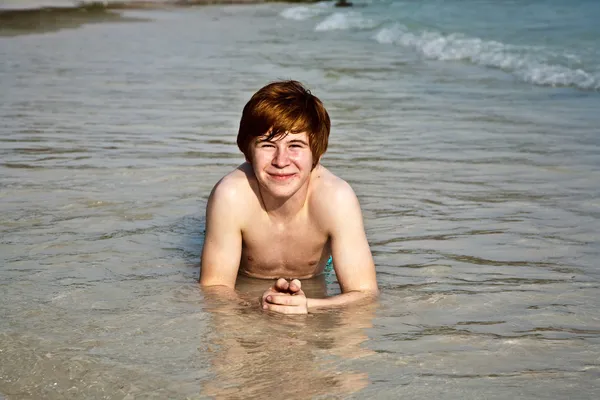 Счастливый мальчик с рыжими волосами наслаждается прекрасным пляжем — стоковое фото