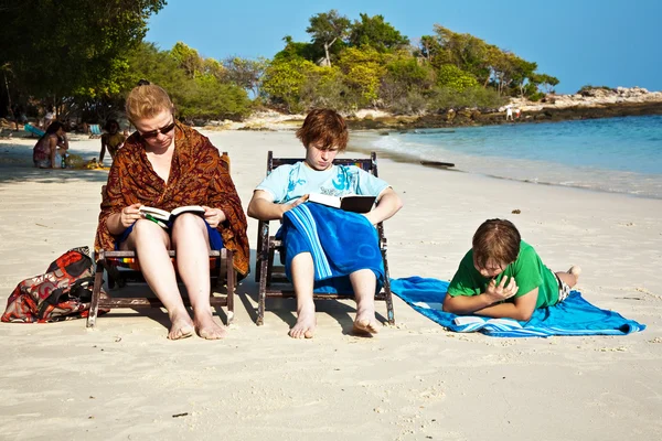 Семья наслаждается солнцем, расслабляясь, сидя на пляже и r — стоковое фото