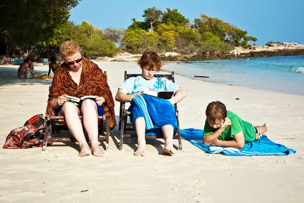 Familia está disfrutando del sol, relajarse, sentarse en la playa y r —  Fotos de Stock