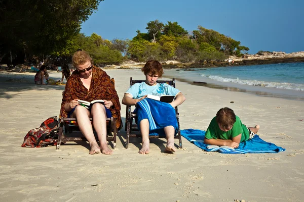 Família está desfrutando do sol, relaxante, sentado na praia e r — Fotografia de Stock