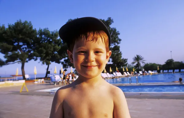 Jovem poy sorri e desfruta da área da piscina no hotel — Fotografia de Stock
