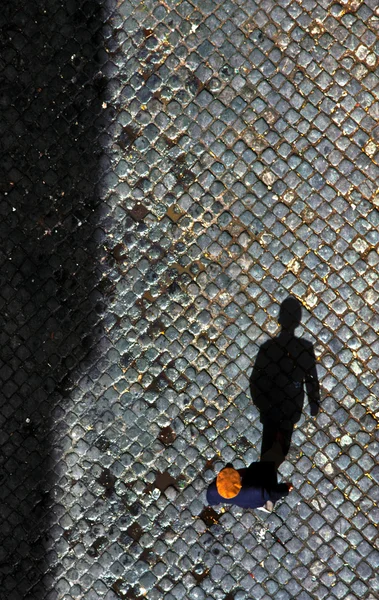 Homem caminhando sobre pedra de calhau em Lisboa com a sua sombra — Fotografia de Stock