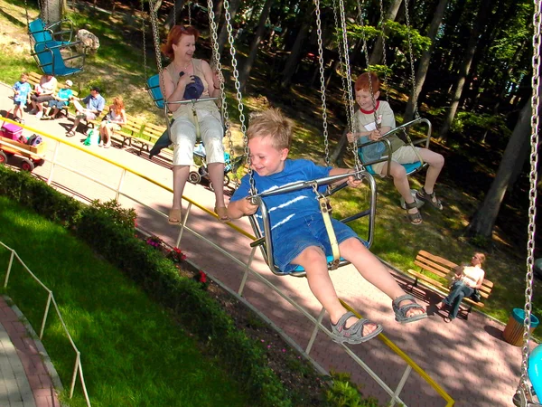 Kind met moeder hebben plezier in de stoel van de carousel — Stockfoto