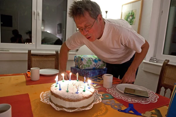 Человек задувает свой праздничный торт — стоковое фото