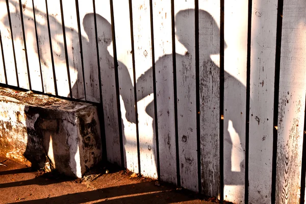 A fiú anyja egy fából készült kerítés a árnyékában — Stock Fotó
