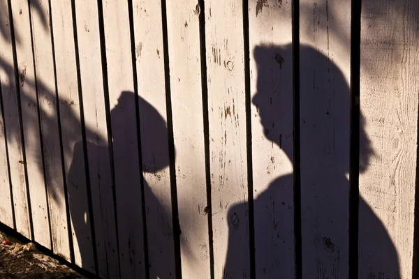 Schaduw van een jongen met moeder op een houten hek — Stockfoto