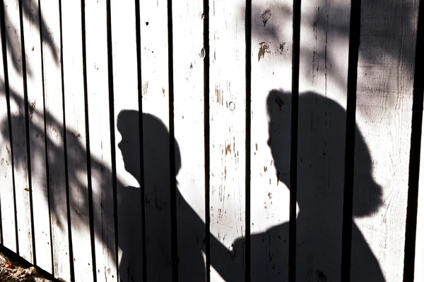 Sombra de un niño con madre en una valla de madera — Foto de Stock