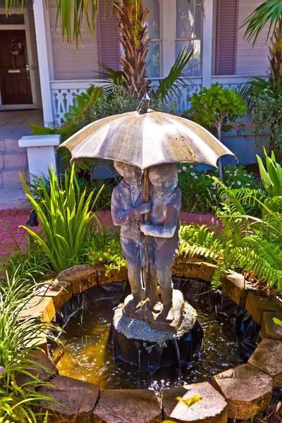 Bir şemsiye ile çocuk muzzl çeşme suyu ile çeşme — Stok fotoğraf
