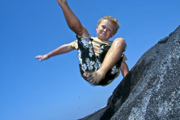 Хлопчик весело стрибає в дюнах пляжу в океані — стокове фото