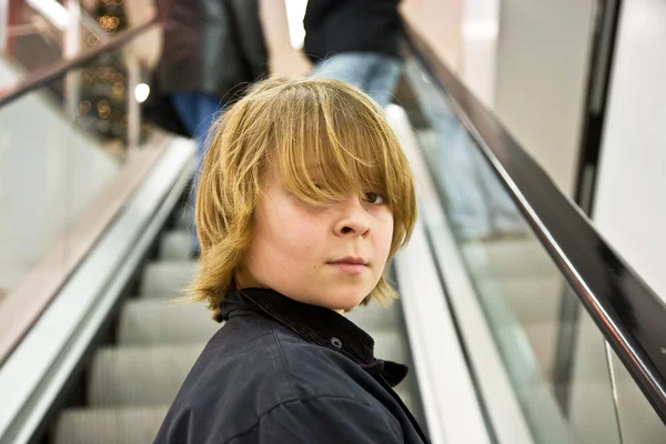 Criança está sorrindo auto confiante em uma escada em um shopping — Fotografia de Stock