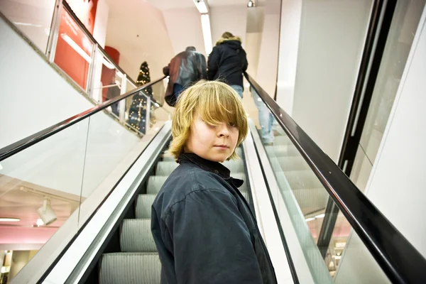 Çocuk kendi kendine güvenen bir alışveriş merkezinde bir merdiven üzerinde gülümsüyor — Stok fotoğraf