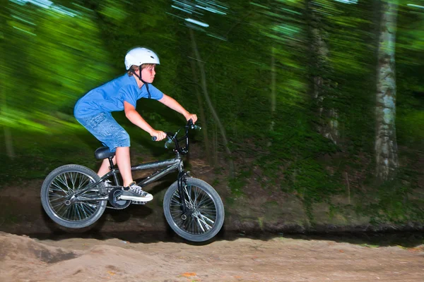 Ребенок веселится, прыгая с мотоцикла через рампу — стоковое фото