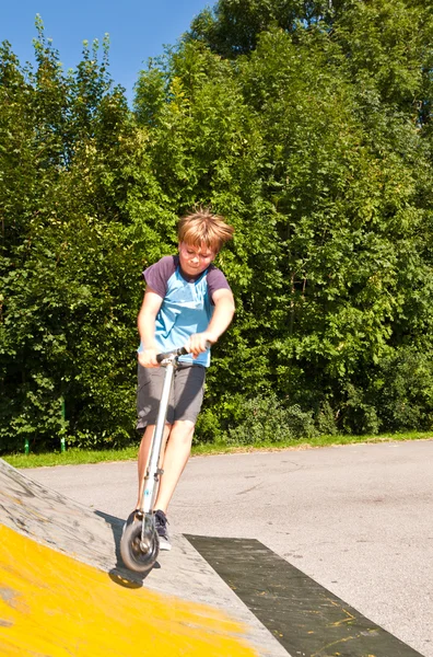 Rapaz se diverte montando sua scooter — Fotografia de Stock