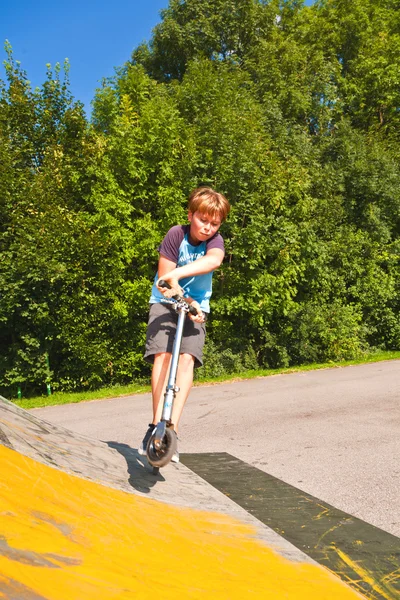 Rapaz se diverte montando sua scooter — Fotografia de Stock