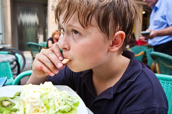 Criança gosta de sorvete sentado ao ar livre em uma mesa — Fotografia de Stock