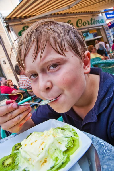 Child enjoys ice cream sitting outdoors at a table — Stock Photo, Image