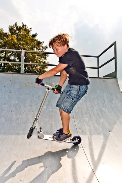 Junge springt mit Roller in Rohr — Stockfoto