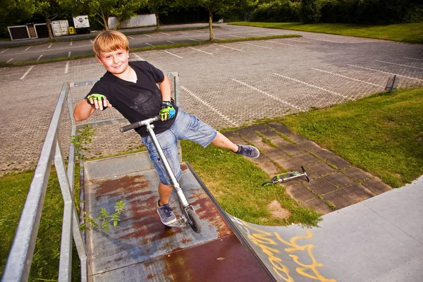 Boy is jumping with scooter in pipe — Stock Photo, Image