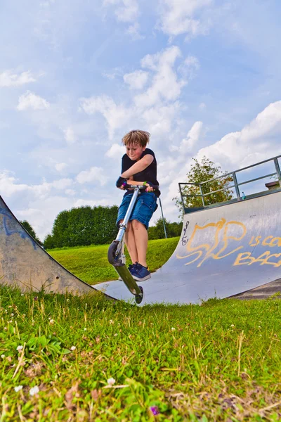 Мальчик прыгает со скутера в трубу — стоковое фото