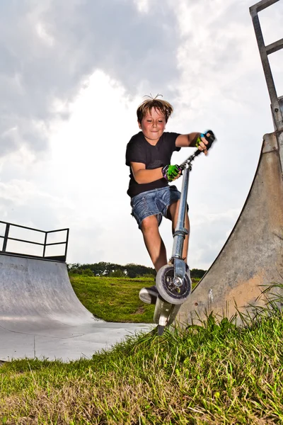 Мальчик прыгает со скутера в трубу — стоковое фото