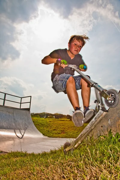 Boy is jumping with scooter in pipe — Stock Photo, Image