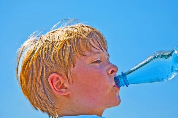 Boy is sweating and thursty and drinks mineral water — Stock Photo, Image