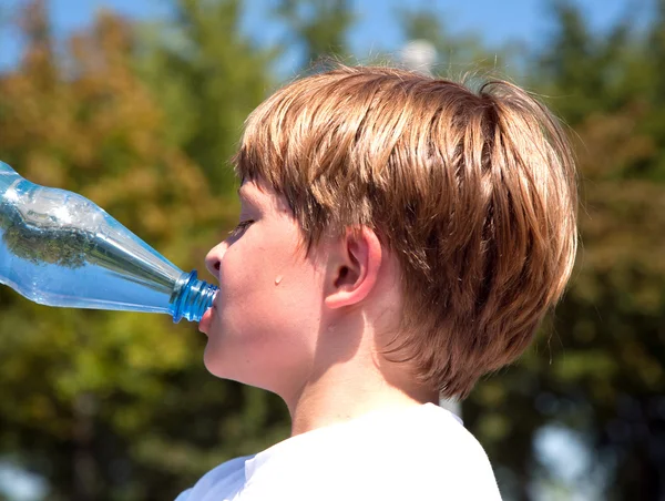 Pojken är svettning och törstiga och dricker mineralvatten — Stockfoto