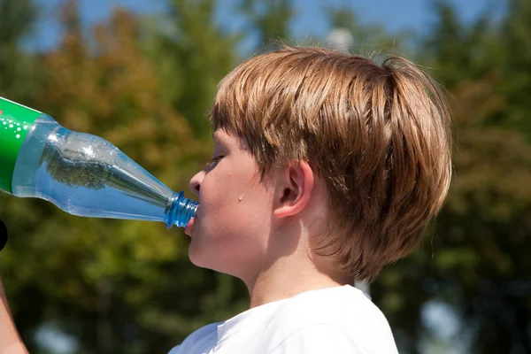 Pojken är svettning och törstiga och dricker mineralvatten — Stockfoto
