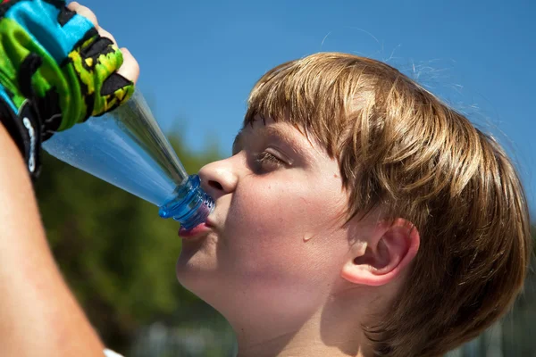 Boy is sweating and thursty and drinks mineral water — Stock Photo, Image