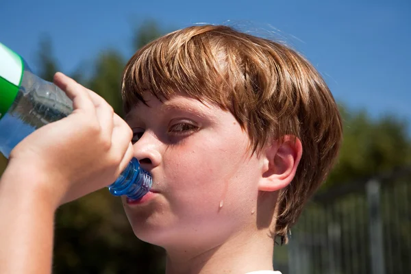 Jongen is zweten en thursty en mineraal water drinkt — Stockfoto