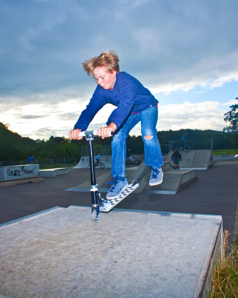 Мальчик прыгает на скутере через рампу — стоковое фото