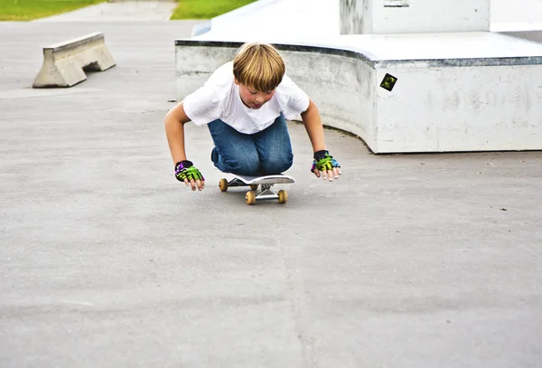 Menino se diverte patinando de joelhos com skate — Fotografia de Stock