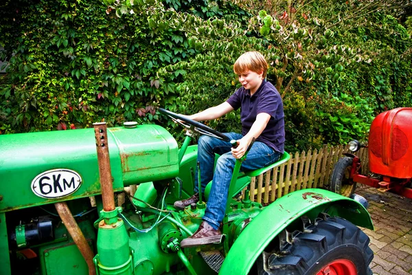 Boy playing with an old tractor — Stock Photo, Image