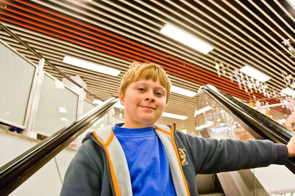 Child on moving staircase looks self confident and smiles — Stock Photo, Image